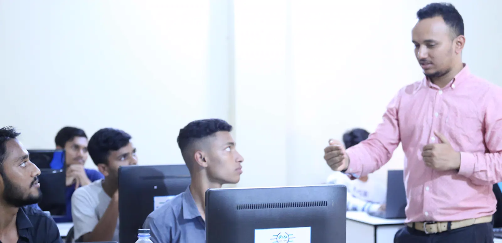 A FILP trainer talking to a student at his monitor